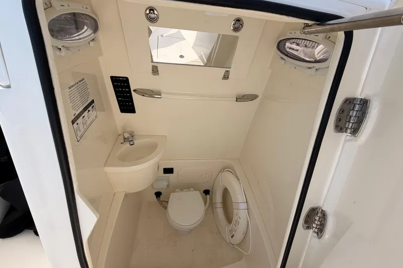 Slide: The Image of 2024 Cobia 262 Center Console boat interior with sink, toilet, and portholes. - 14