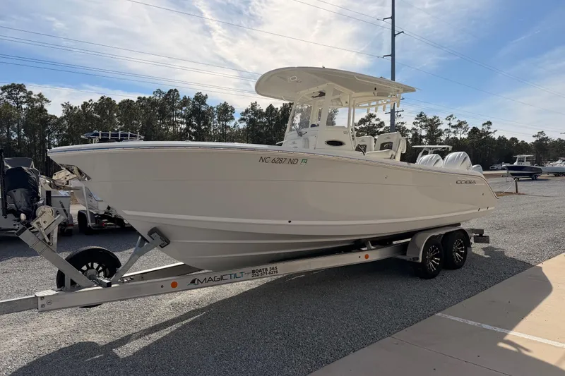 Slide: The Image of 2024 Cobia 262 Center Console boat on trailer, parked outdoors under clear sky. - 6