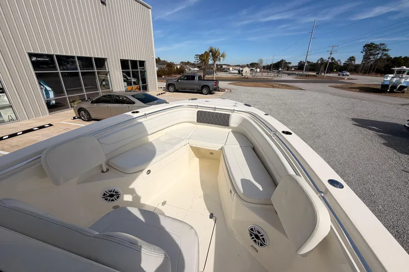 Slide: The Image of 2024 Cobia 262 Center Console boat with spacious seating, displayed outdoors near a showroom. - 9