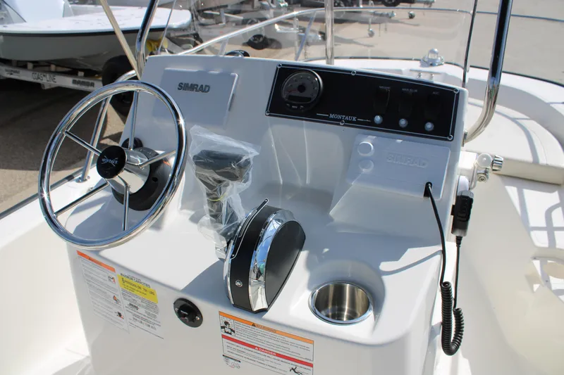 Slide: The Image of 2026 Boston Whaler 150 Montauk boat console with steering wheel and controls. - 12
