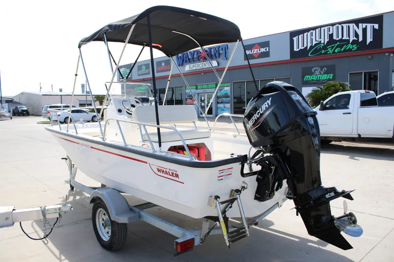 Slide: The Image of 2026 Boston Whaler 150 Montauk boat with Mercury engine, parked outside dealership. - 22