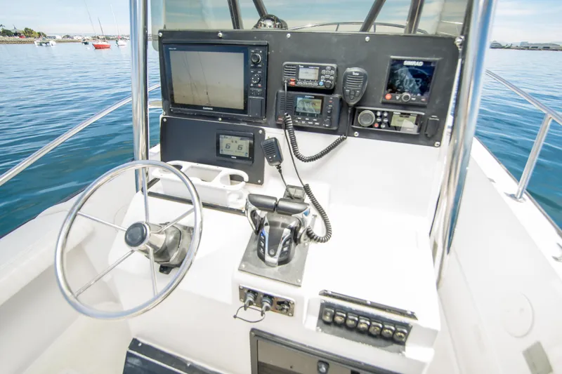 Slide: The Image of 1997 Boston Whaler 24 Outrage helm with navigation equipment and steering wheel on calm water. - 10