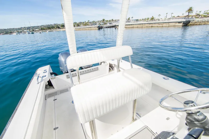 Slide: The Image of 1997 Boston Whaler 24 Outrage boat on calm water, featuring white seating and steering wheel. - 12
