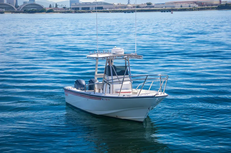 Slide: The Image of 1997 Boston Whaler 24 Outrage boat on calm blue water, cityscape in background. - 2