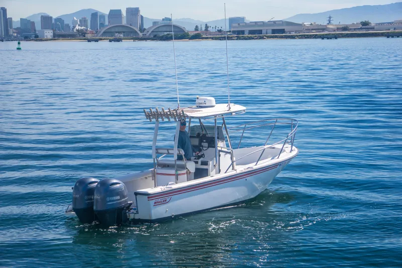 Slide: The Image of 1997 Boston Whaler 24 Outrage boat on calm water with city skyline in background. - 3