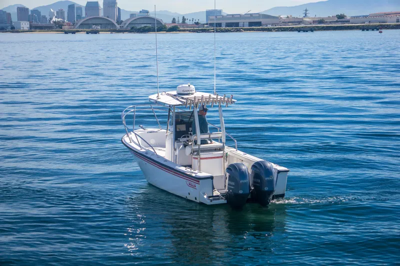 Slide: The Image of 1997 Boston Whaler 24 Outrage boat on calm water with city skyline in background. - 4