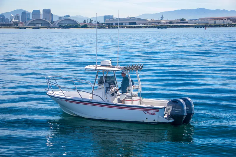 Slide: The Image of 1997 Boston Whaler 24 Outrage boat on calm water with city skyline in background. - 5