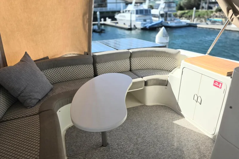 Slide: The Image of 2000 McKinna 48 Pilothouse yacht interior with curved seating and table, docked at marina. - 10