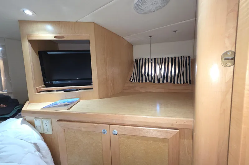 Slide: The Image of 2000 McKinna 48 Pilothouse interior with TV, wooden cabinetry, and striped curtains. - 43
