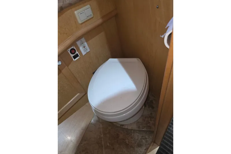 Slide: The Image of Toilet in 2000 McKinna 48 Pilothouse yacht bathroom, featuring wooden paneling and control switches. - 47