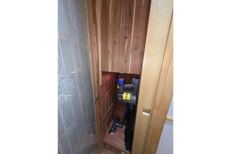 Slide: The Image of Wooden storage compartment on 2000 McKinna 48 Pilothouse, housing a vacuum cleaner. - 52