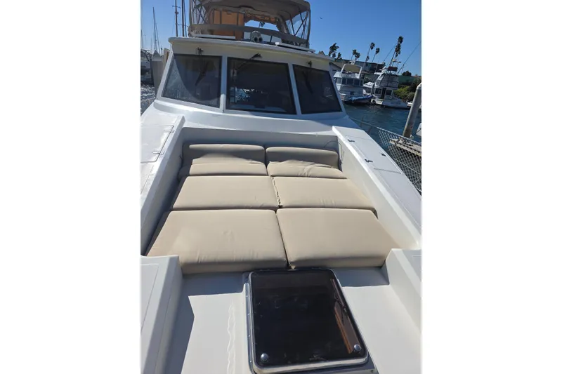 Slide: The Image of 2000 McKinna 48 Pilothouse yacht with beige sun pads on deck, docked in marina. - 6