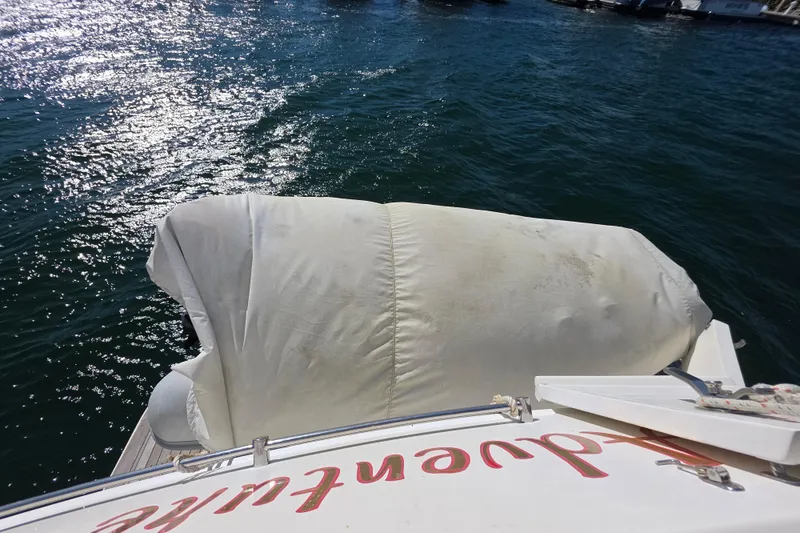 Slide: The Image of 2000 McKinna 48 Pilothouse yacht with covered equipment on deck, docked by shimmering water. - 63