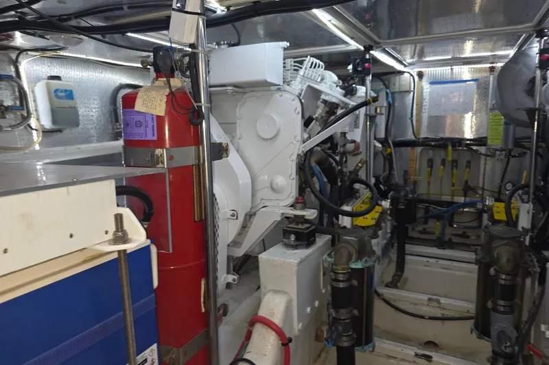 Slide: The Image of Engine room of a 2000 McKinna 48 Pilothouse yacht, featuring machinery and fire extinguisher. - 65
