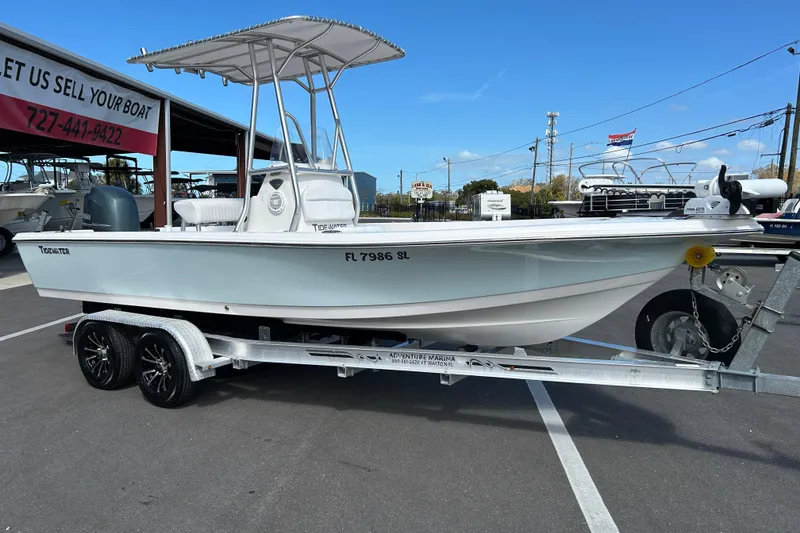 The Image of 2014 Tidewater 2100 Bay Max boat on trailer at marina, under clear blue sky. - 1