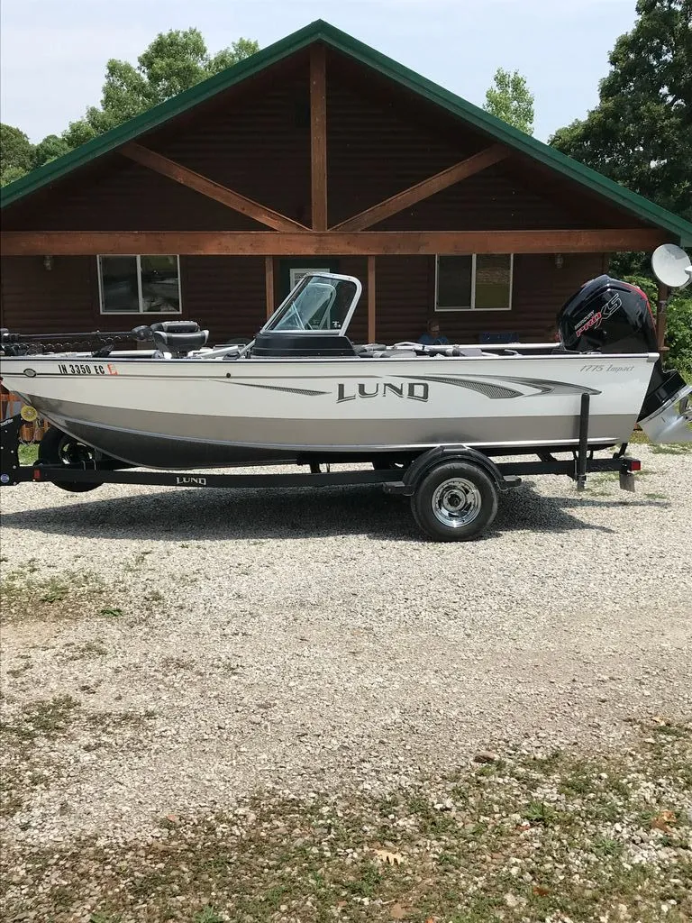 The Image of 2019 Lund 1775 Impact boat parked in front of a wooden cabin. - 0