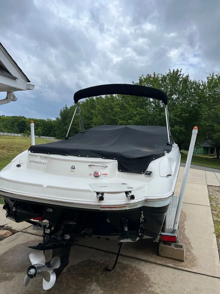 Slide: The Image of 2018 Stingray 235 LR boat on trailer, covered, parked outdoors. - 14