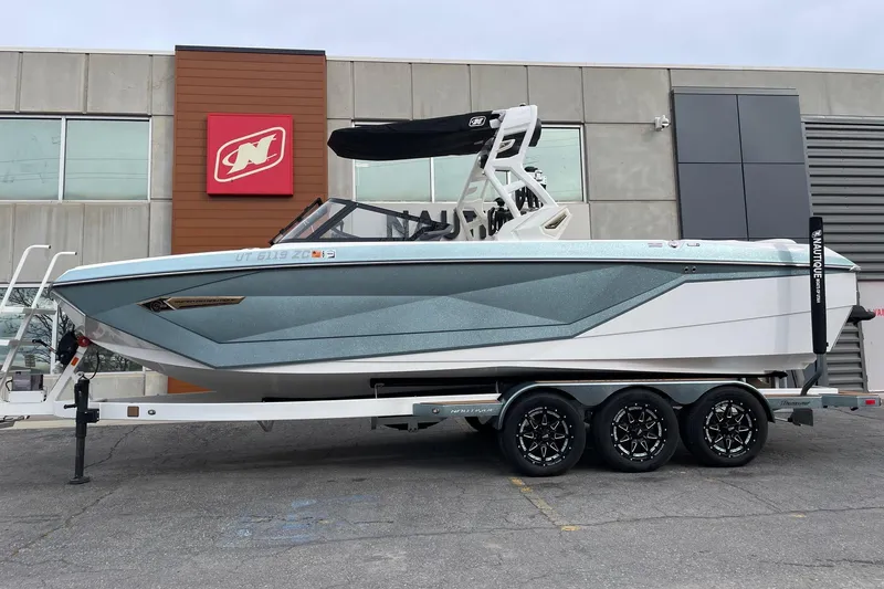 The Image of 2021 Nautique Super Air Nautique G25 boat on trailer outside dealership. - 1