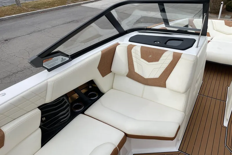 Slide: The Image of 2021 Nautique Super Air Nautique G25 interior with white and tan seating, cup holders, and sleek design. - 10