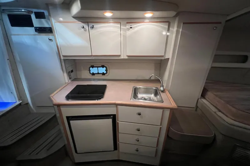 Slide: The Image of 1997 Maxum 2800 SCR boat interior kitchen with sink, stove, and storage cabinets. - 14