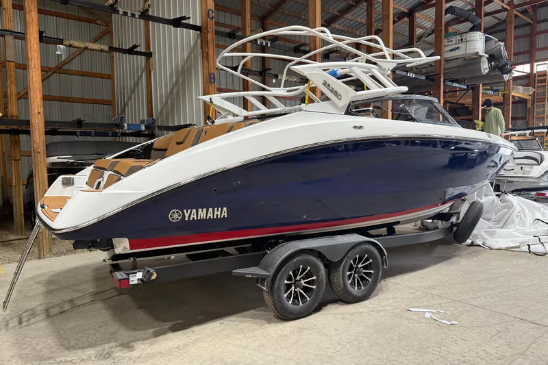 Slide: The Image of 2025 Yamaha Boats 252SD in storage, sleek design, blue and white exterior, on trailer. - 1