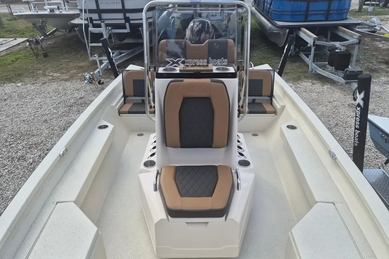 Slide: The Image of 2026 Xpress H20 boat interior with tan and black seating, parked on gravel. - 9