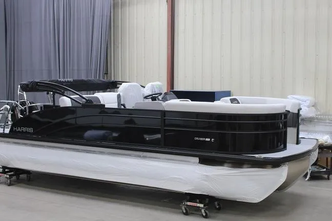 The Image of 2026 Harris Cruiser 210 pontoon boat in a showroom, featuring sleek black design. - 0