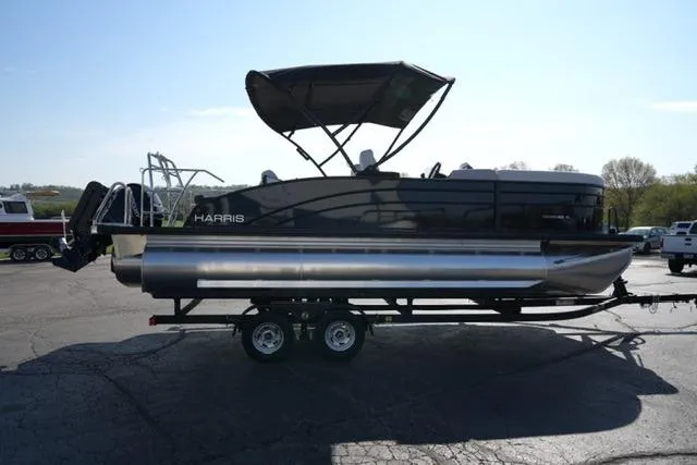 Slide: The Image of 2026 Harris Cruiser 210 pontoon boat on trailer, parked outdoors under clear sky. - 10