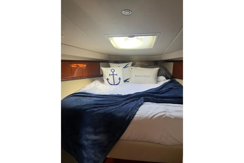 Slide: The Image of Cozy cabin interior of 2005 Sea Ray 390 Express Cruiser with nautical-themed bedding. - 14