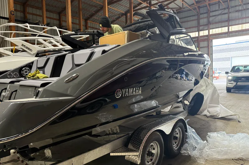 Slide: The Image of 2025 Yamaha Boats 222XD in a warehouse, on a trailer, with a person inspecting it. - 2