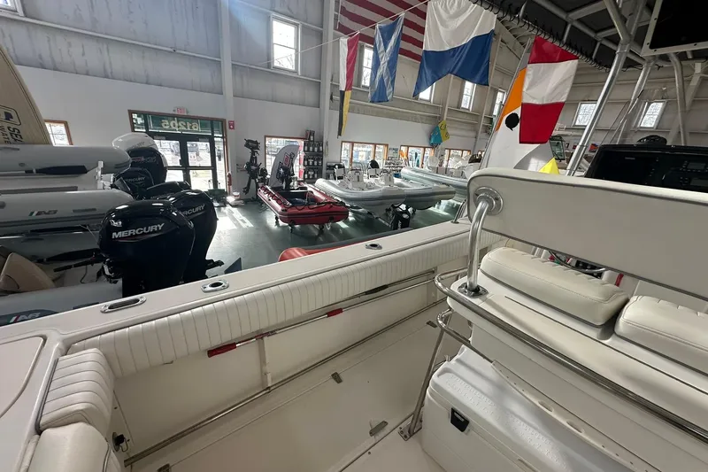 Slide: The Image of 2001 Boston Whaler 26 Outrage boat interior in showroom with flags and Mercury engines. - 12
