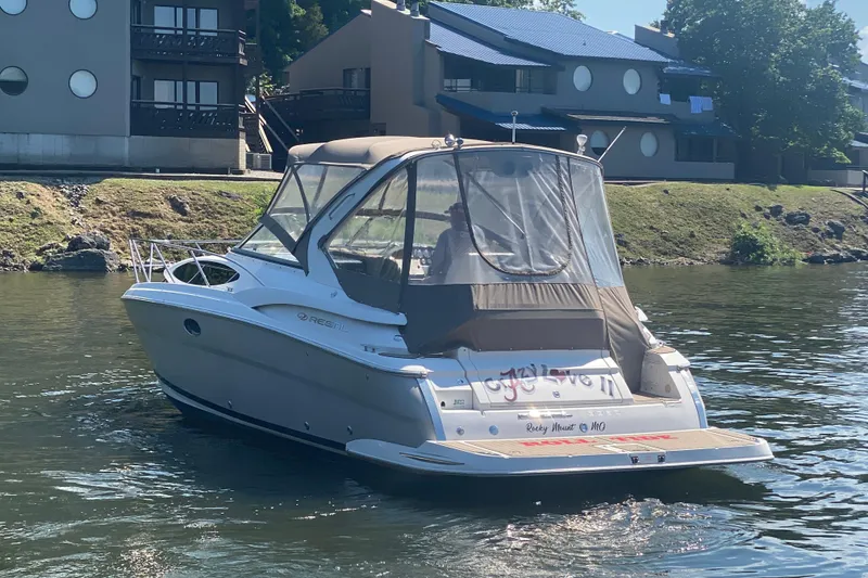 Slide: The Image of 2008 Regal 3360 Window Express boat cruising on a calm river near modern buildings. - 3