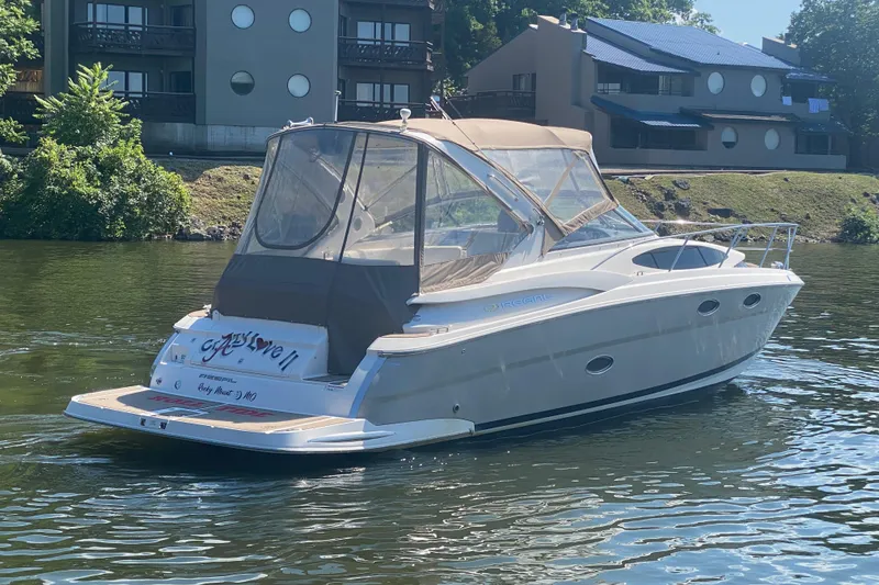 Slide: The Image of 2008 Regal 3360 Window Express boat on calm water near residential buildings. - 2