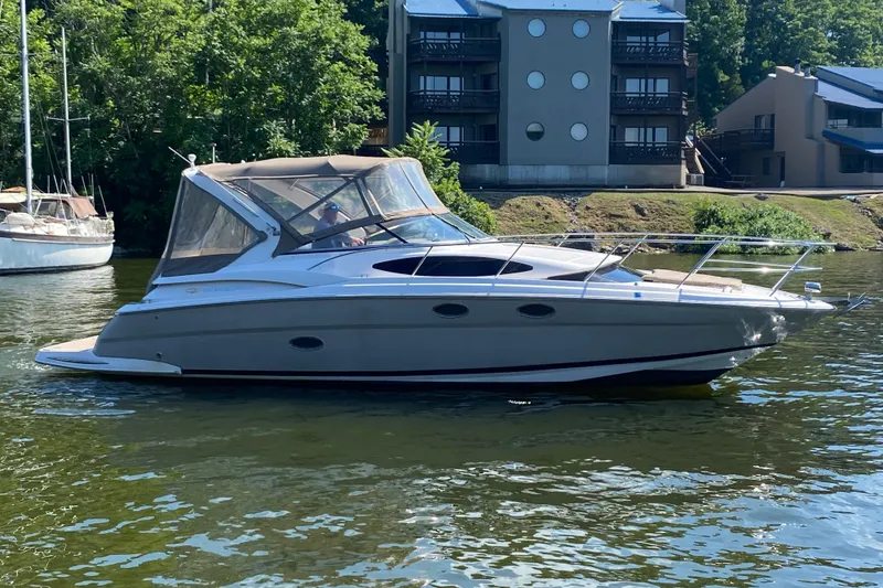 The Image of 2008 Regal 3360 Window Express boat on a calm river near residential buildings. - 0