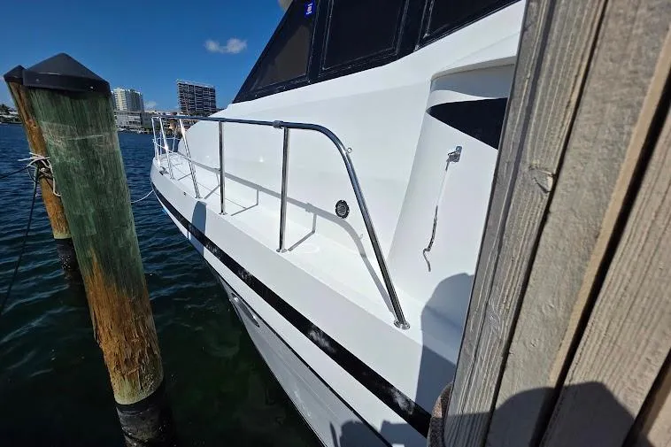 Slide: The Image of 1993 McKinna 48 Pilothouse yacht docked, showcasing sleek white exterior and railing. - 12