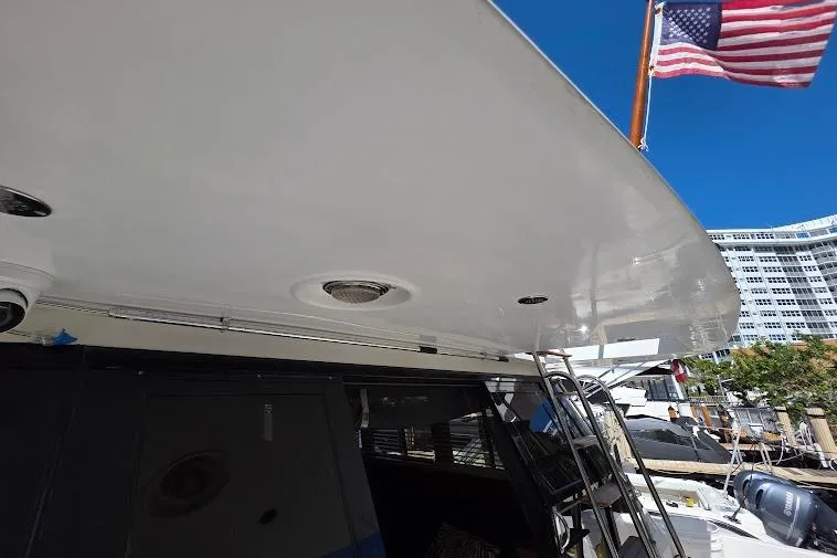 Slide: The Image of 1993 McKinna 48 Pilothouse yacht with American flag, docked under clear blue sky. - 17