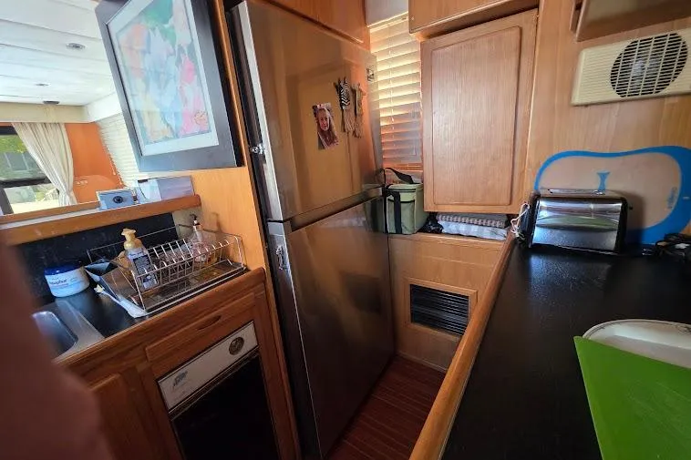 Slide: The Image of Kitchen area of 1993 McKinna 48 Pilothouse with stainless steel appliances and wooden cabinetry. - 25