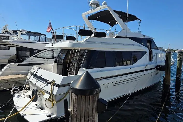 Slide: The Image of 1993 McKinna 48 Pilothouse yacht docked at marina, featuring sleek design and American flag. - 3
