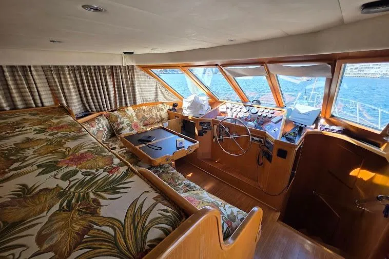 Slide: The Image of Interior of 1993 McKinna 48 Pilothouse with floral upholstery and wooden helm, overlooking the sea. - 41