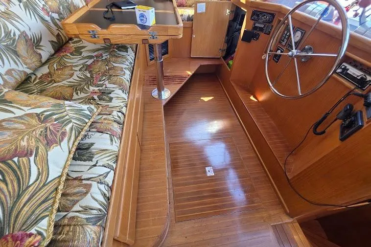 Slide: The Image of 1993 McKinna 48 Pilothouse interior with floral seating and wooden steering area. - 57
