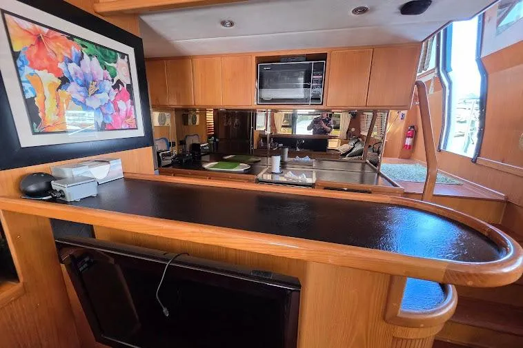 Slide: The Image of 1993 McKinna 48 Pilothouse interior with kitchen, wooden cabinetry, and colorful artwork. - 58