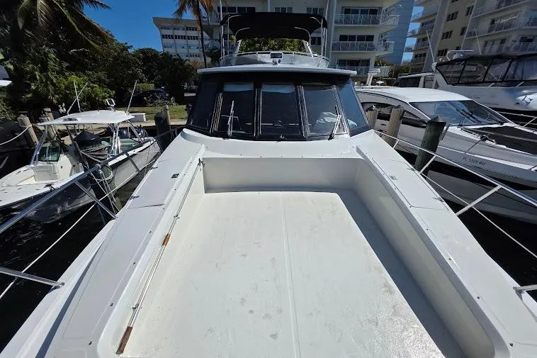Slide: The Image of 1993 McKinna 48 Pilothouse yacht docked, showcasing spacious deck and sleek design. - 67