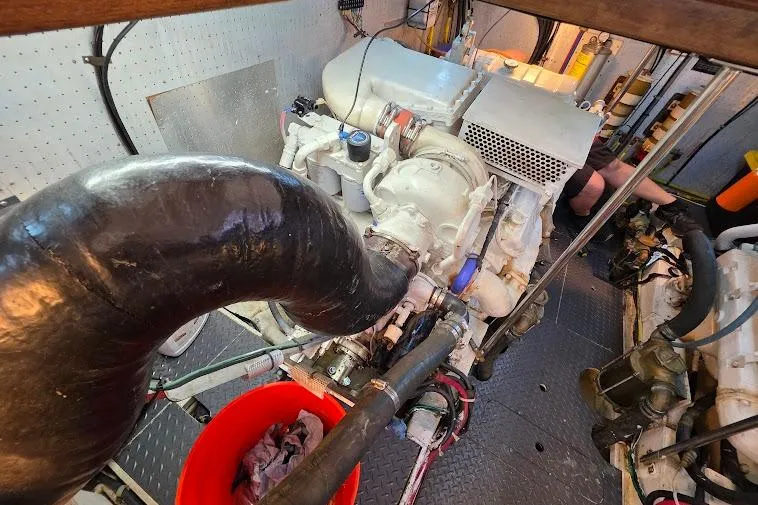 Slide: The Image of Engine room of a 1993 McKinna 48 Pilothouse yacht, featuring mechanical components and hoses. - 72