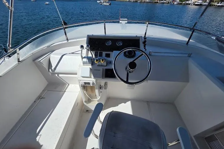 Slide: The Image of 1993 McKinna 48 Pilothouse helm with steering wheel and controls, overlooking serene waters. - 80