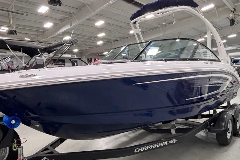 Slide: The Image of 2026 Chaparral 21 SSi boat in showroom, sleek design, blue and white exterior. - 15