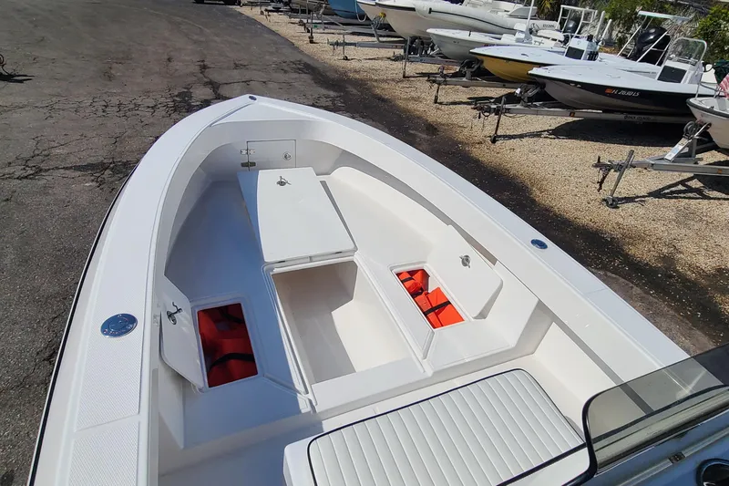 Slide: The Image of 2025 Paramount 21 boat with open storage compartments and life jackets, parked on a trailer. - 12