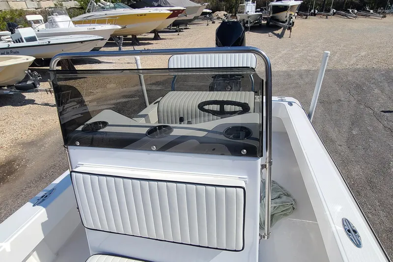 Slide: The Image of 2025 Paramount 21 boat interior with steering wheel and seating, parked among other boats. - 16