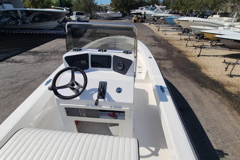 Slide: The Image of 2025 Paramount 21 boat interior with steering wheel and control panel in a boatyard. - 17