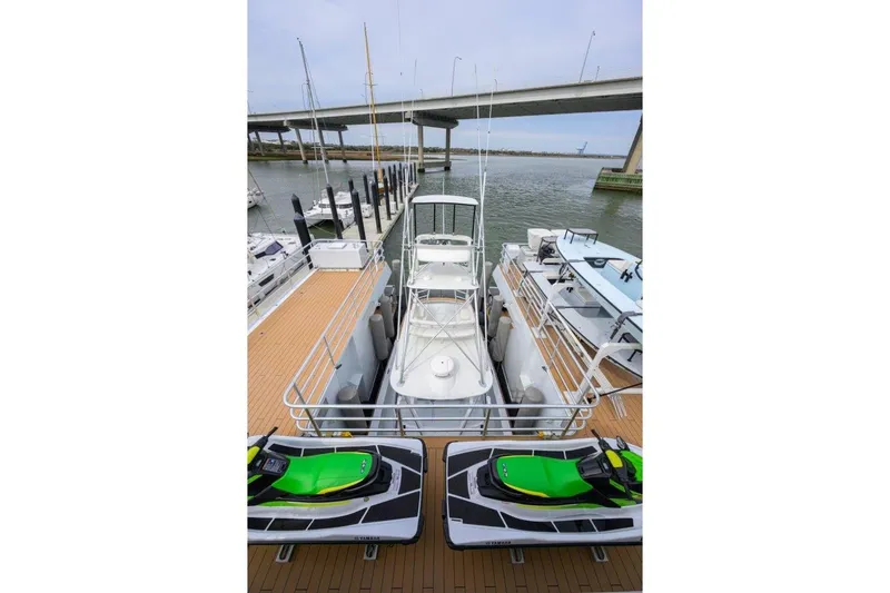Slide: The Image of 2011 C & G Boatworks Explorer docked with jet skis, under a bridge. - 13