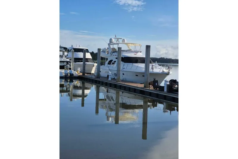 Slide: The Image of 2009 Grand Harbour 66 Motoryacht docked at a serene marina, reflecting on calm water. - 5